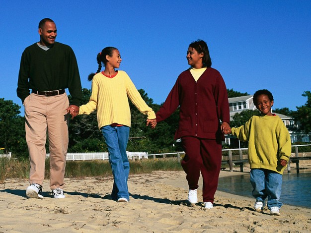 African American family walking on lakefront beach